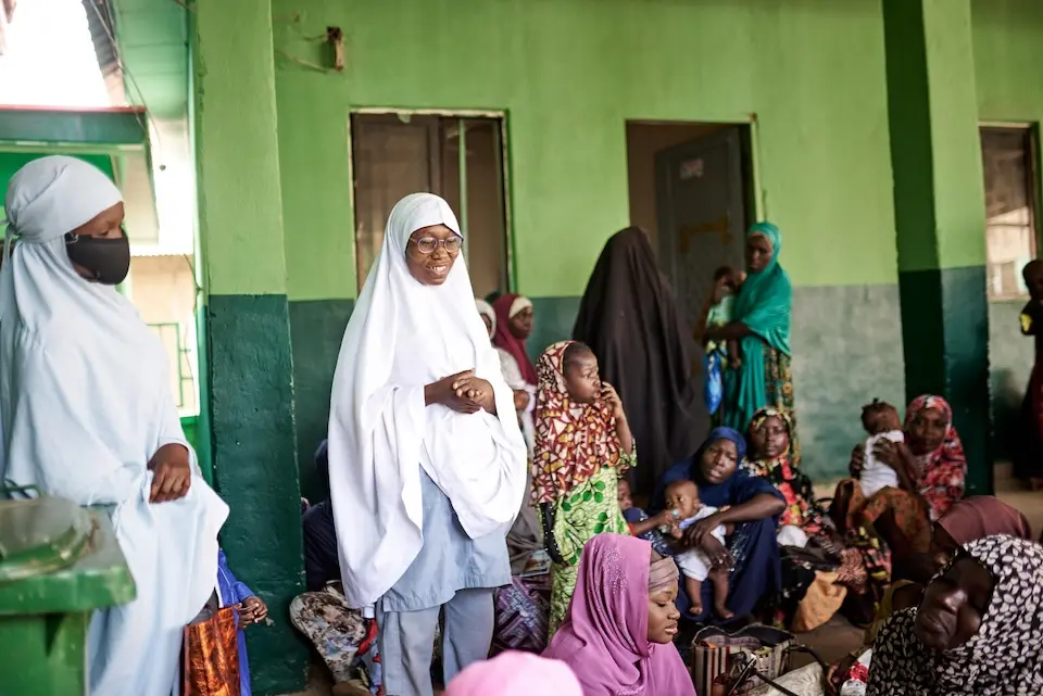 On March 5, 2023, health care worker Hafsat Isah, center, speaks to nursing mothers who brought their children for vaccination in Kofan Rini PHC, Sokoto State, Nigeria, in