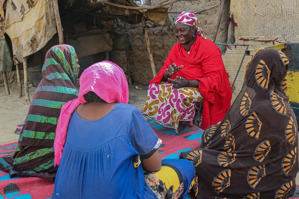 Outside a house in Mali, Aissata, center, speaks to a group of women in her community about the importance of being vaccinated against tetanus to protect the health of future children.