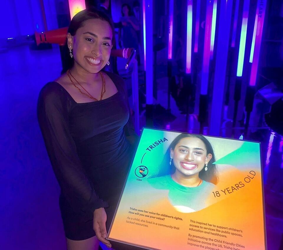 Trisha, 18, stands beside a photo of herself at Heart Strings, an interactive exhibit designed to illustrate the impact of UNICEF's work for children worldwide.