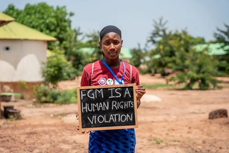 A girl in The Gambia holds a sign protesting against female genital mutilation.