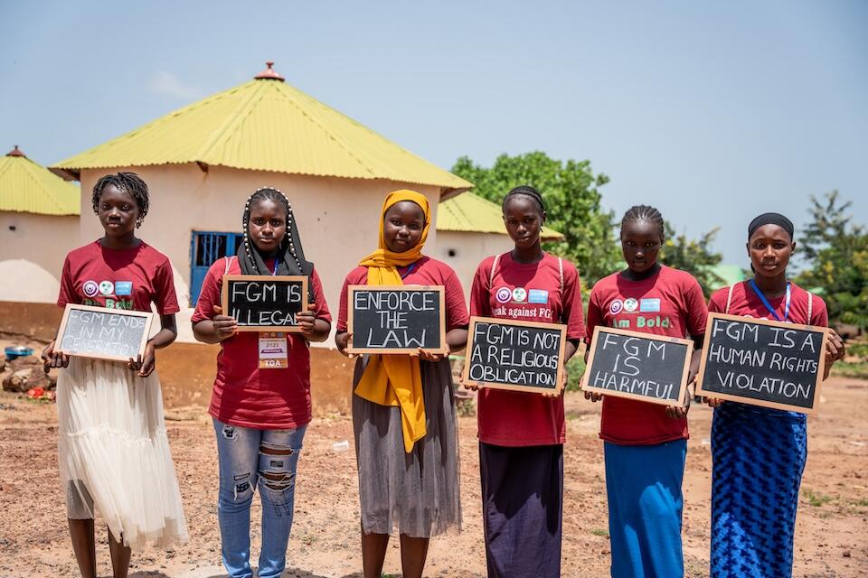 Girls in The Gambia hold signs protesting against female genital mutilation.