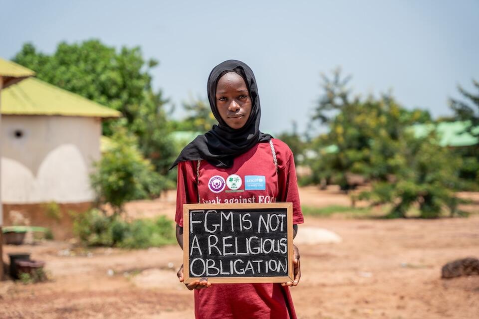 A girl in The Gambia holds a sign protesting against female genital mutilation.