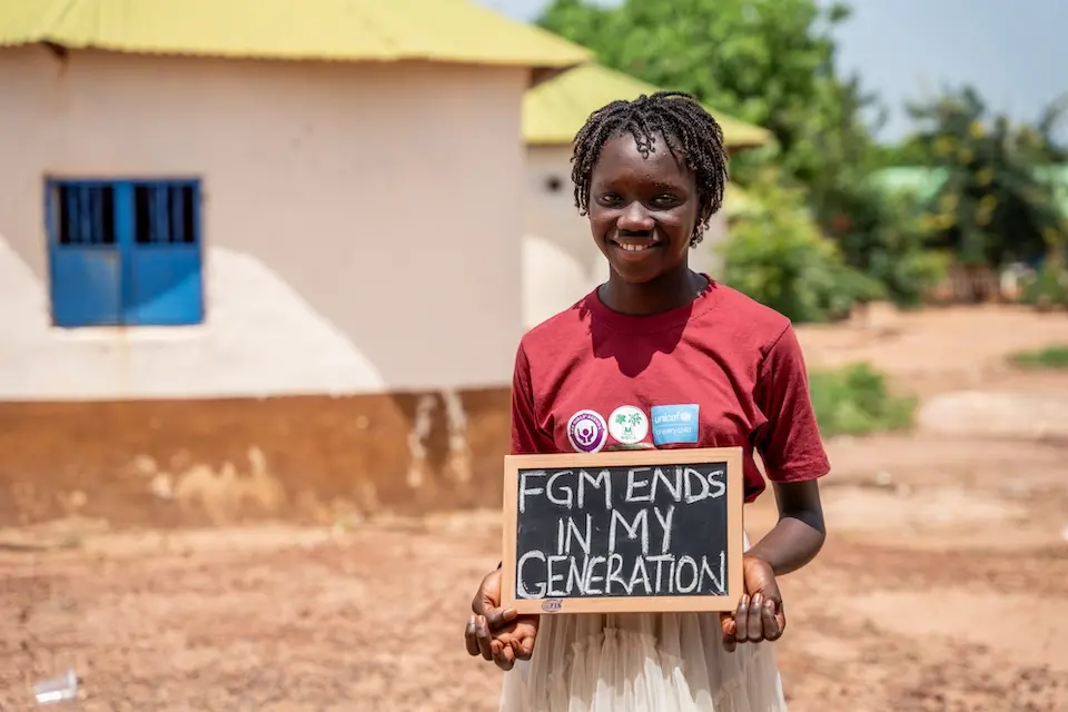 A girl in The Gambia holds a sign protesting against female genital mutilation.