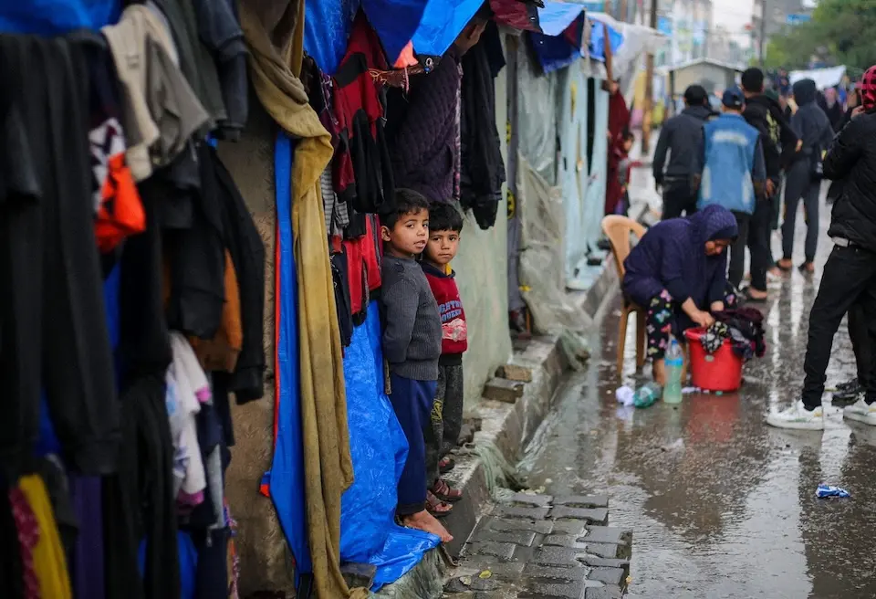 On a rainy day in the city of Rafah in the southern Gaza Strip, children stand outside the tent where they are staying with their families after being displaced by violence.