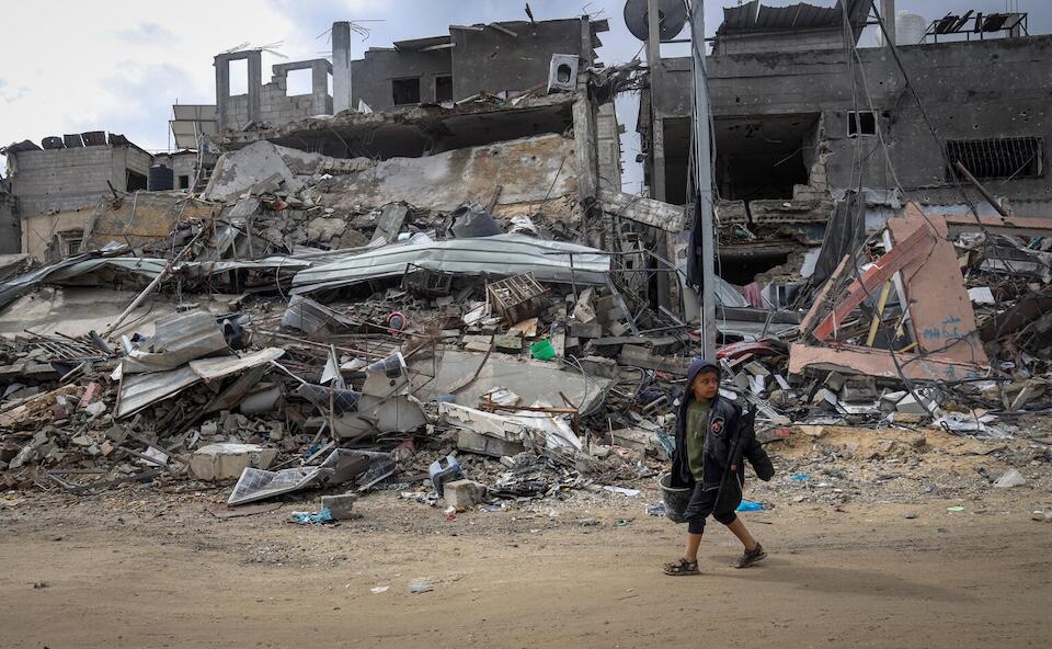 Nine-year-old Tamer walks through the rubble of his destroyed neighborhood in Khan Younis, southern Gaza Strip. 
