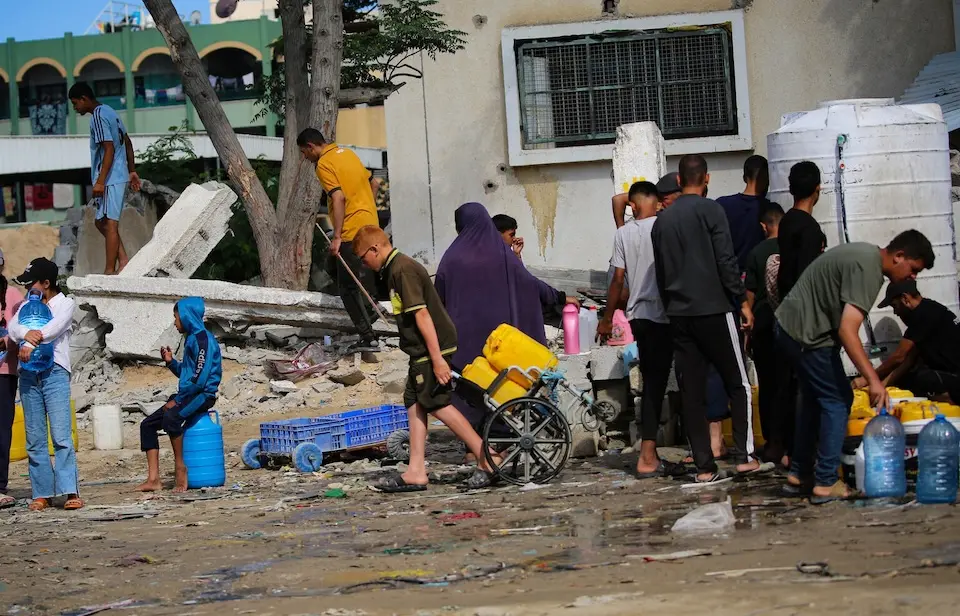 Among the rubble, children collect water in Khan Younis city, southern Gaza Strip.