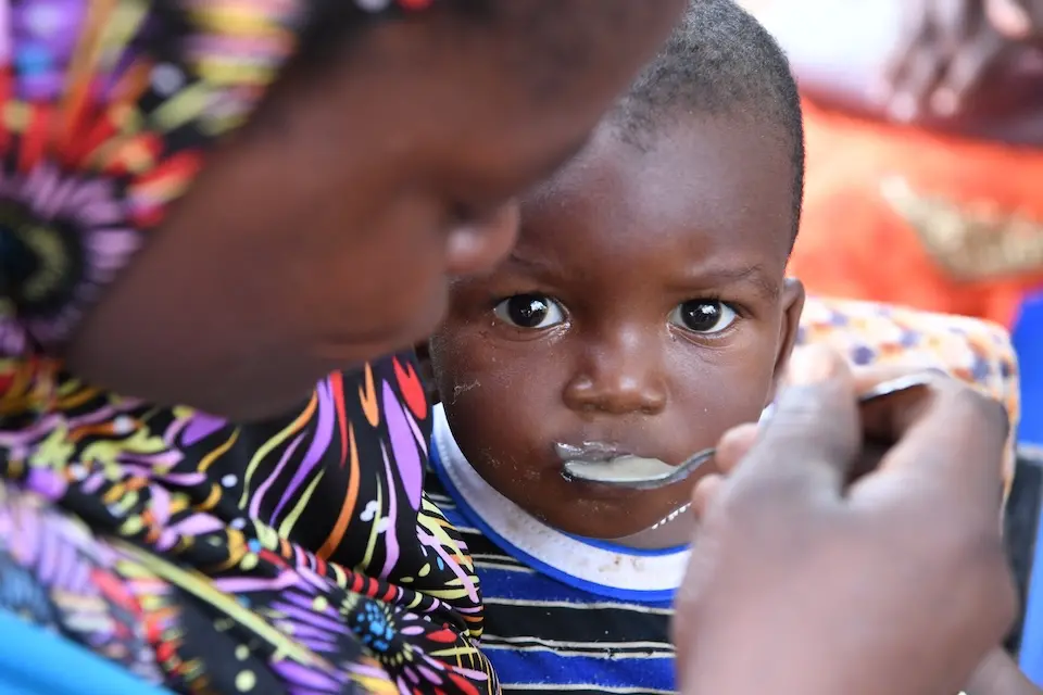 A mother in Ngolo village, northern Burkina Faso, feeds her child porridge enriched with micronutrient powder supplied by UNICEF.