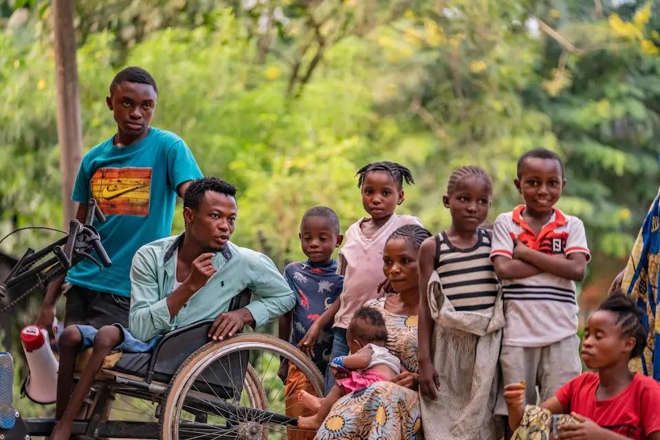 Rajabu Vambise (second from left), polio survivor and UNICEF-supported community worker, talks to a family in his neighborhood about vaccinating children against polio in Kindu, Maniema province, Democratic Republic of the Congo, on March 27, 2024.