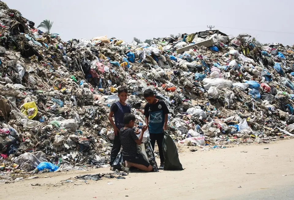 Children carry plastic bags and search inside a waste dump in Rafah, southern Gaza Strip, on May 18, 2024.