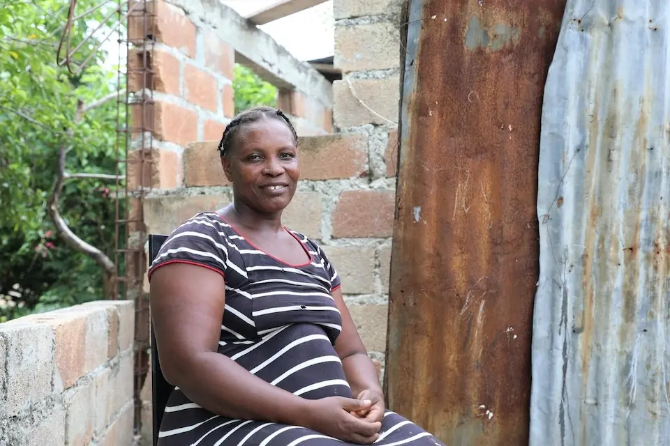 Bien Aimé sits in front of the house she recently rented in Léogâne, Haiti.