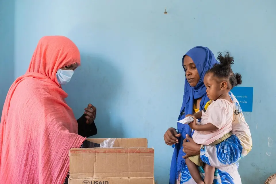 A displaced mother from Khartoum receives sachets of Ready-to-Use Therapeutic Food (RUTF) at a UNICEF-supported mobile clinic in Adama locality, Atbara, River Nile State, Sudan.