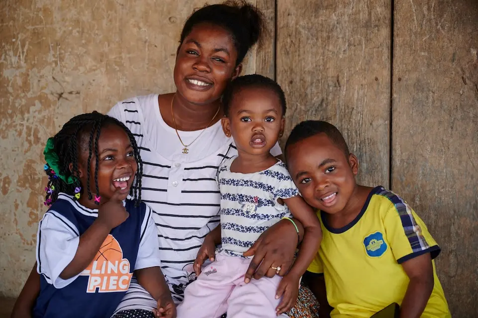 During a measles campaign, Faustina, 21, sits holding her children at a vaccination outreach in a village in Ghana, West Africa.