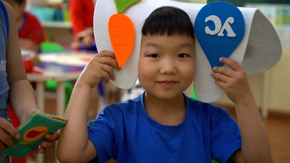 A kindergarten student in Ulaanbaatar wears a large white felt tooth as a hat during a classroom activity about dental health in Ulaanbaatar, Mongolia.