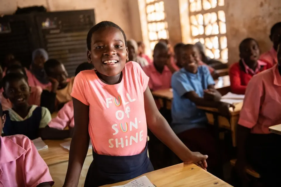 A student stands proudly at her new desk, provided by the K.I.N.D. Fund, at Bwengu Primary School in Malawi.