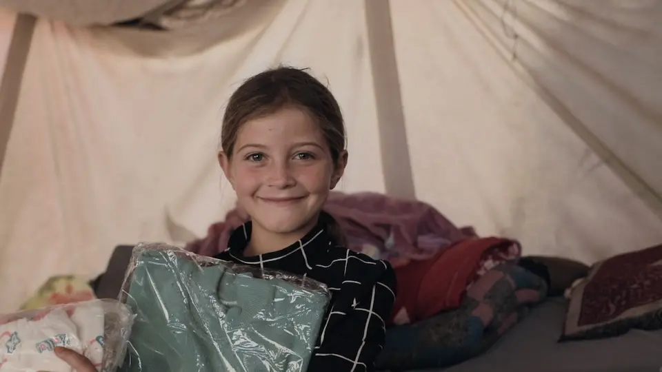 A girl holds winter clothes distributed by UNICEF and partners in Khan Younis, Gaza on Dec. 15, 2024.