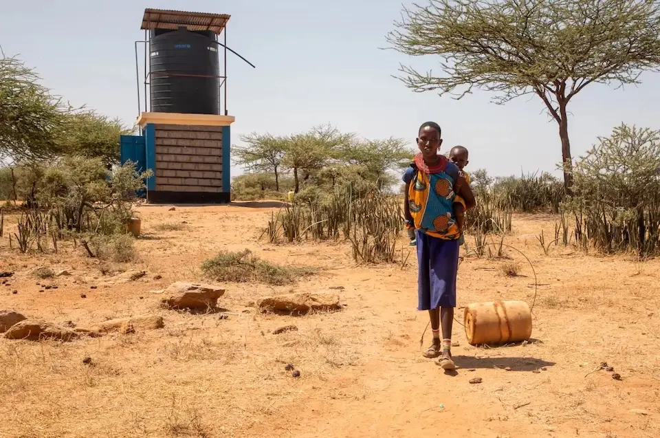 Naram, mother of two, fetches safe water from a new solar-powered water kiosk just steps from her home, a big improvement.