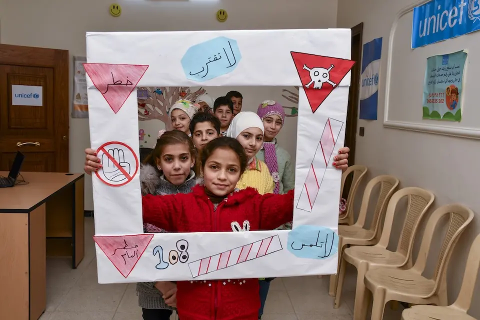 Children hold a special sign representing key lessons shared during an awareness session about the risks of explosive ordnance, at a UNICEF-supported center in Hammorieh, Rural Damascus, Syria.