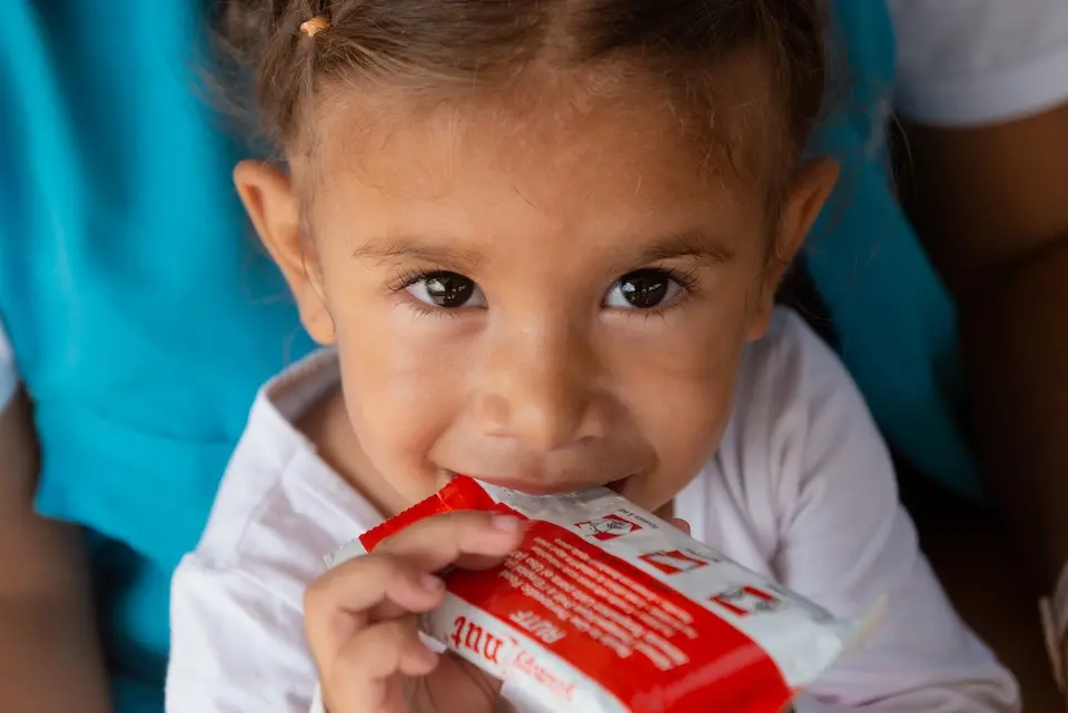 A young migrant child staying in Peru's Tumbes region eats from a packet of UNICEF-supplied Ready-to-Use Therapeutic Food, a form of treatment for acute malnutrition.