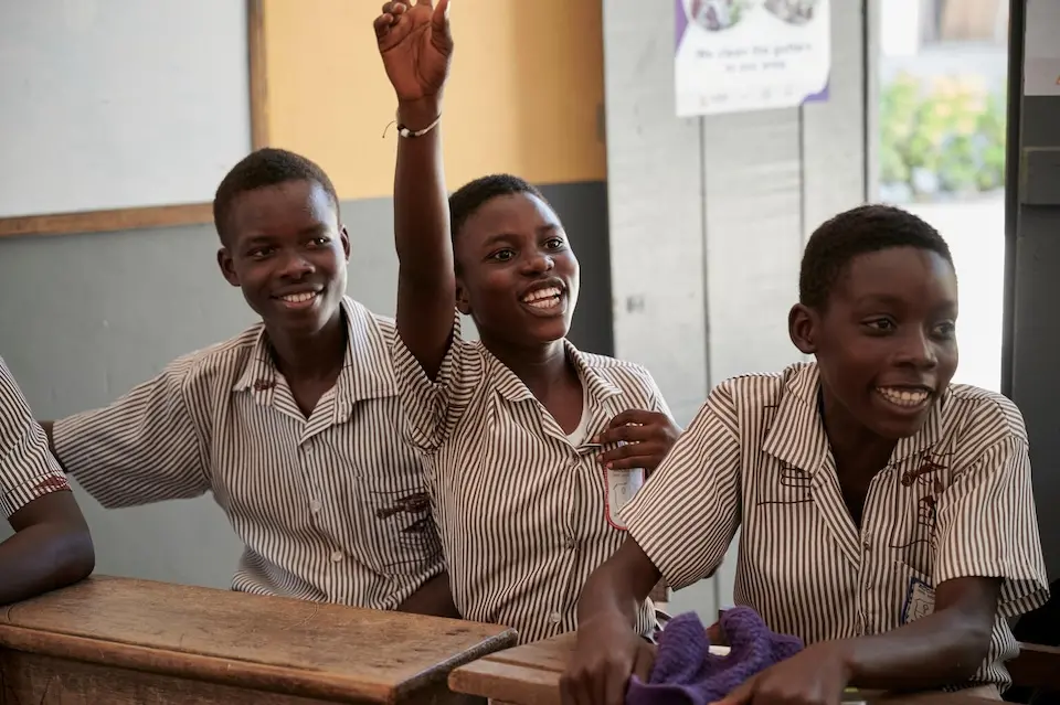 A student raises her hand to answer a question during a lesson at Accra Royal Basic School.