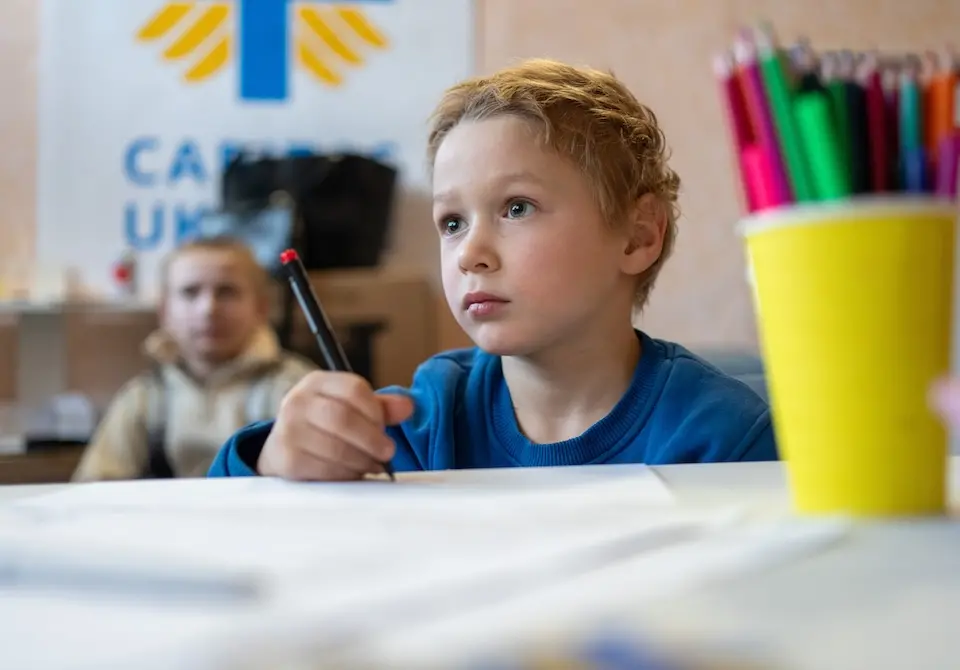 Mykhailo, 4, draws in the children's room of a UNICEF-supported humanitarian service hub in Pavlohrad, Ukraine, after enduring a difficult journey from Shevchenkove in the Donetsk region, where intense fighting forced families to evacuate.