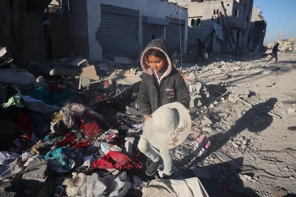 On Jan. 21, 2025, Jana stands amid the rubble of her destroyed home in Rafah, holding a hat — one of the few objects recovered from the debris.