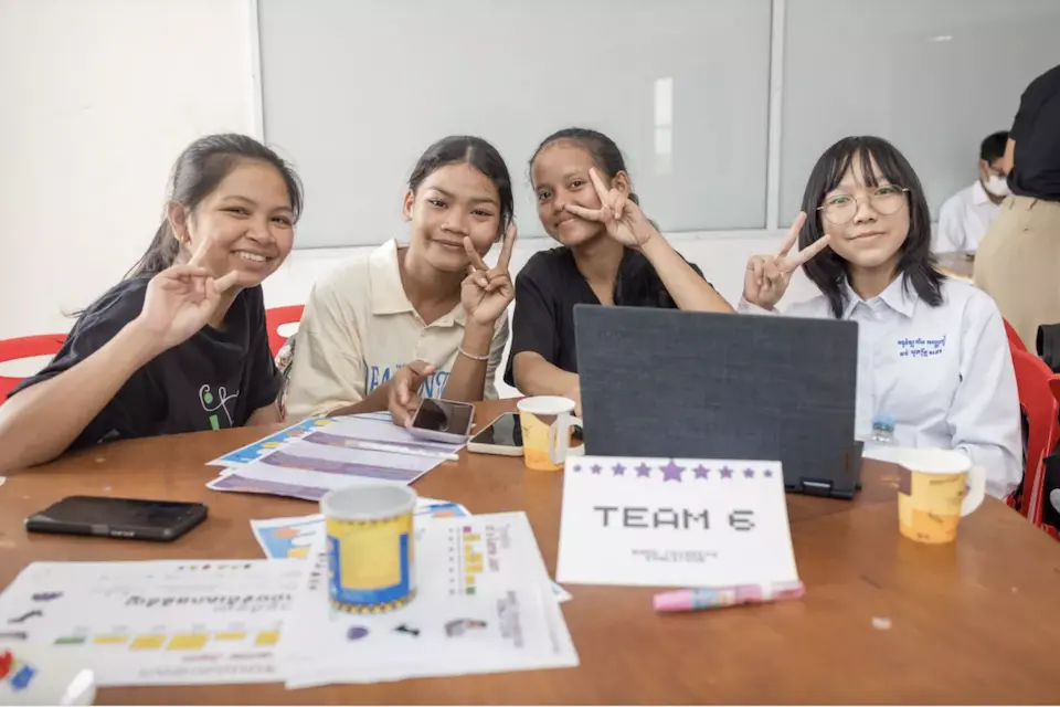 Four girls smile at the camera while working on a project
