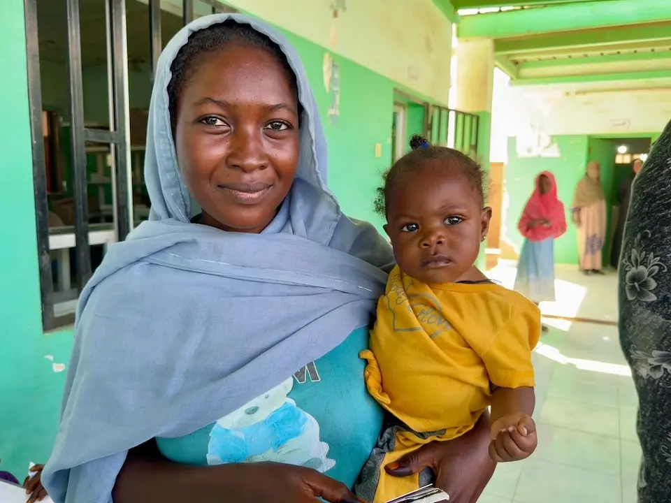 A mother hold her child at the humanitarian cash assistance distribution point in Port Sudan, Sudan.