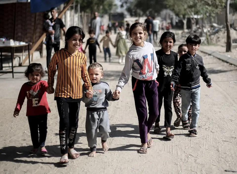 Six children walk hand in hand down a dirt road in Hamad City, Khan Younis, southern Gaza Strip.