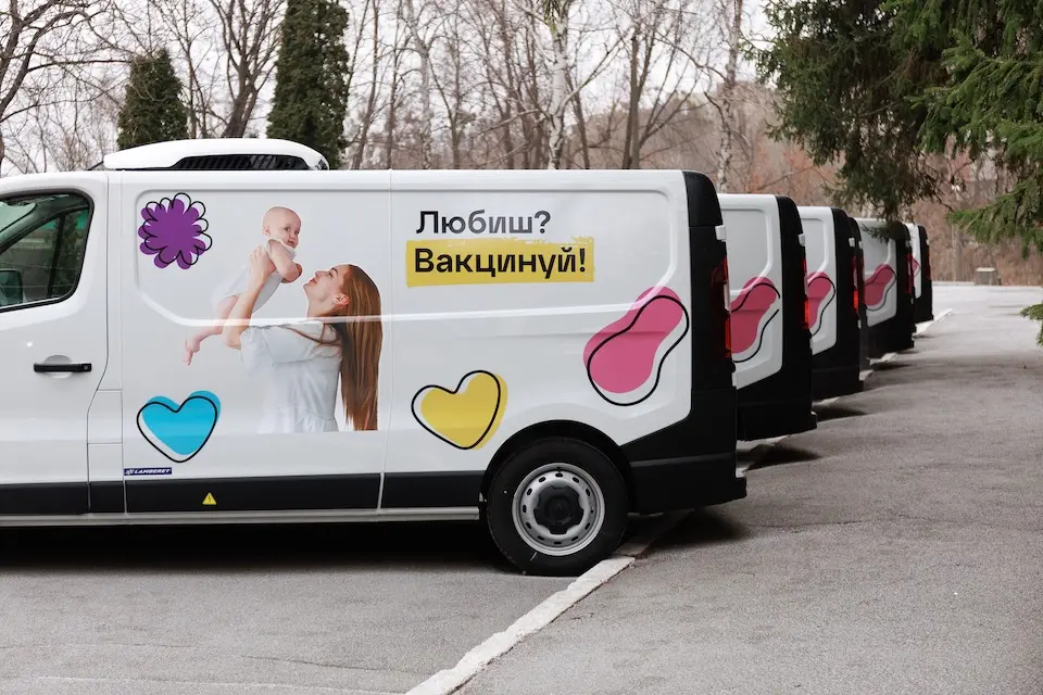 A fleet of refrigerated vaccine vans, procured by UNICEF with donor support, stand ready for deployment; they are equipped with specialized cooling systems to ensure the safe delivery of vaccines, even in areas heavily affected by the war, to protect children's health across the country. The message on the van reads: "Love? Vaccinate!" – underscoring the importance of timely immunization.
