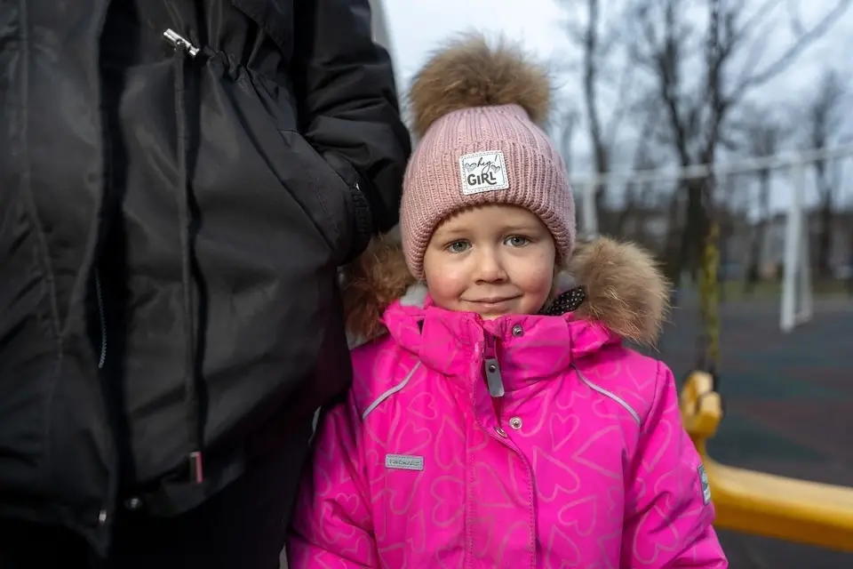 Three-year-old Katya leans against her mother, Alyona, smiling softly, in Balakliia, Ukraine.