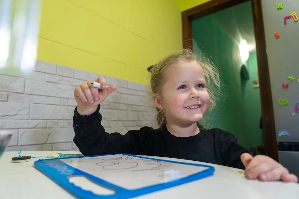 In Balakliia, Ukraine, 3-year-old Katya draws at home, holding her marker carefully.