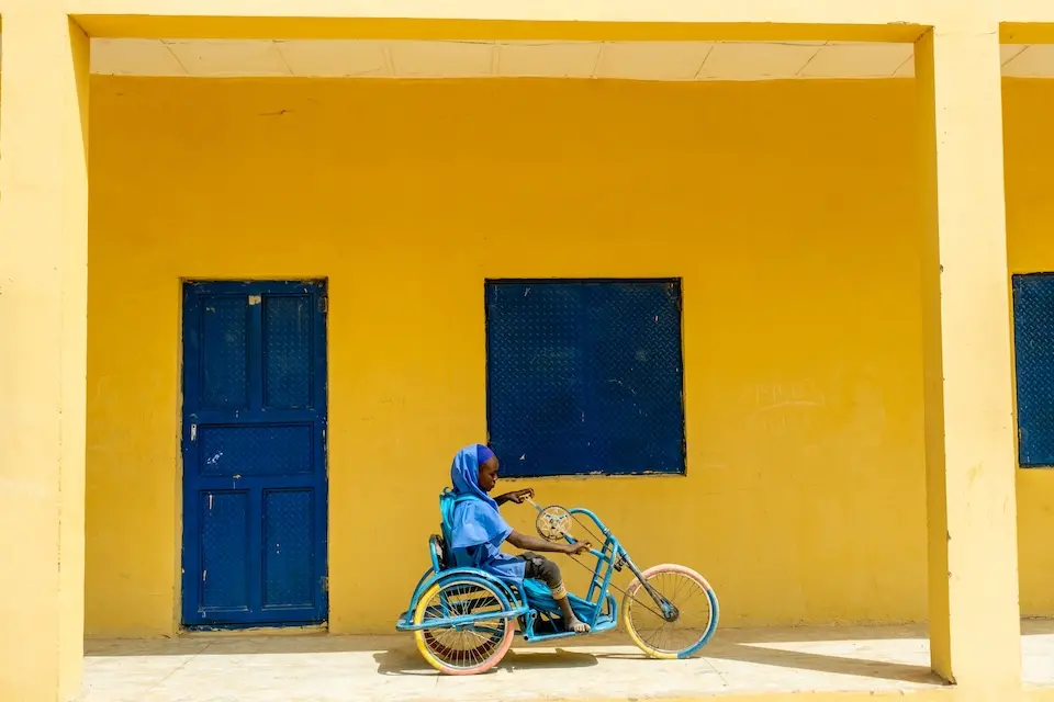 Aisha, 13, rides her handcycle outside Pompomari Primary School in Nigeria.