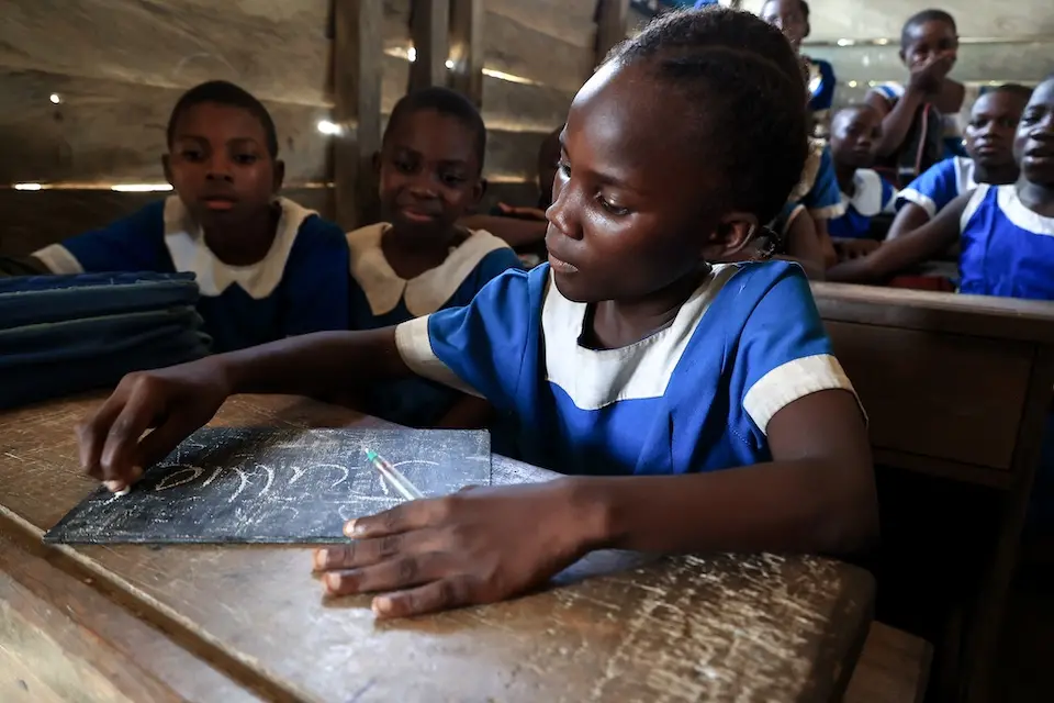 A young student writes on a blackboard in her classroom in Cameroon.