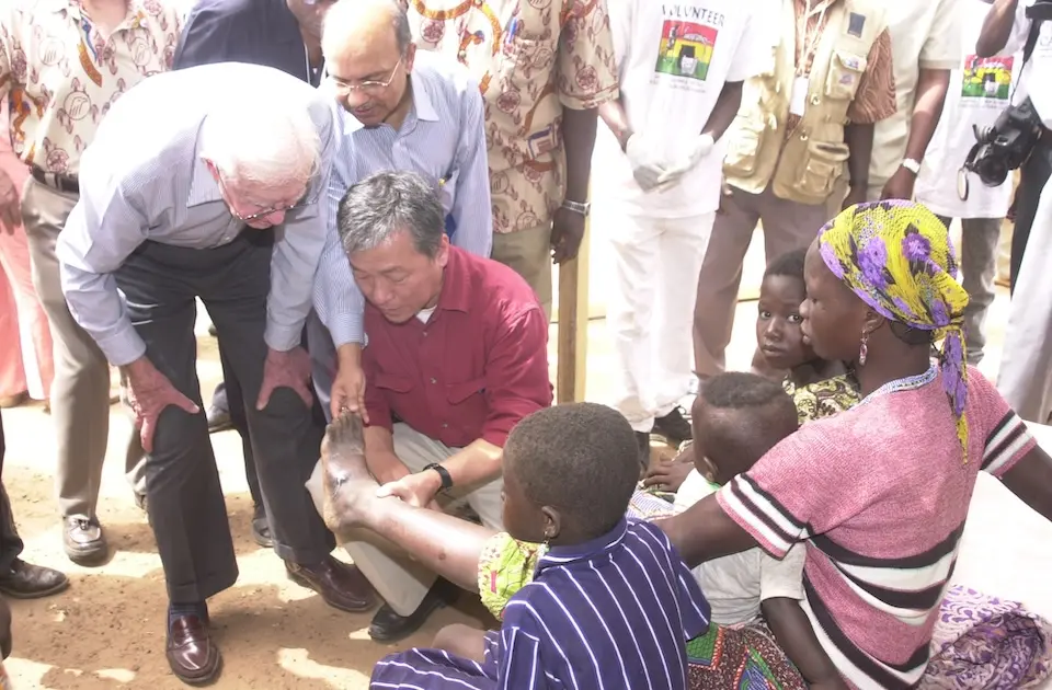 During a 2004 visit to Dashie, a village in northern Ghana, (from left to right) the late former U.S. President Jimmy Carter, former Deputy Executive Director of UNICEF Kul Gautam and former Director-General of WHO Dr. Lee Jong-wook meet with a mother suffering from Guinea worm.