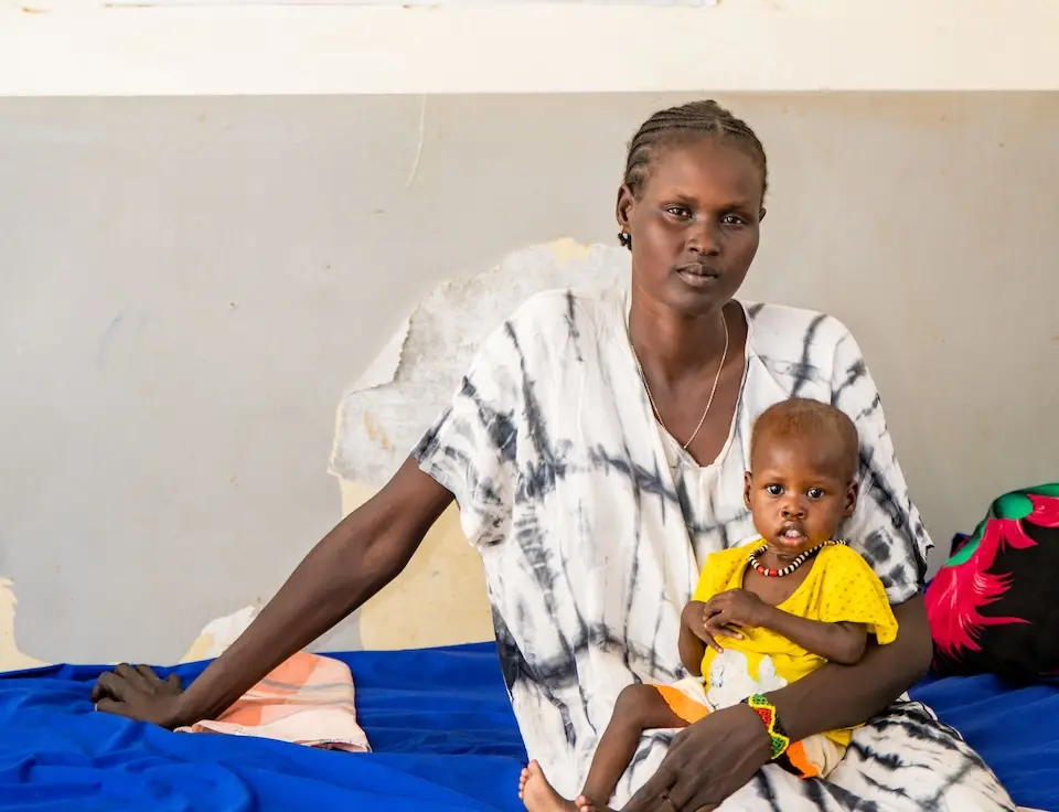 A mother and daughter, refugees from the Sudan war, sit inside a UNICEF-supported nutrition stabilization center in South Sudan.