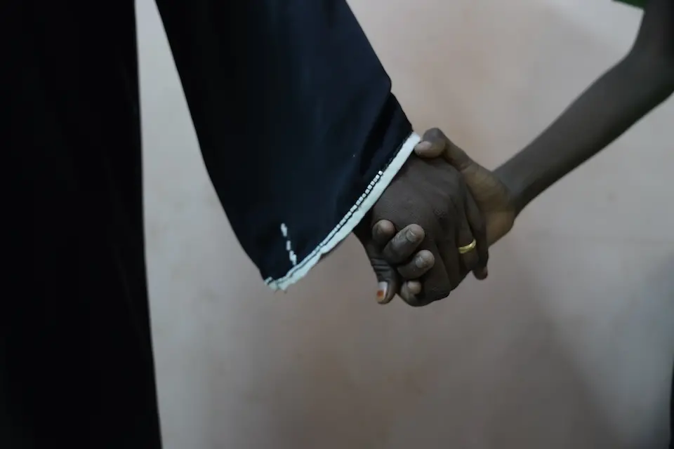 On Dec. 4, 2024 in Sudan, 11-year-old Musa [NAME CHANGED] holds his mother’s hand tightly after visiting the psychologist and social worker helping him deal with the trauma of rape.