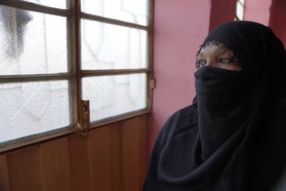 On Dec. 10, 2024 in Sudan, Omnia [NAME CHANGED] peers through the window during a visit to a women’s organization.