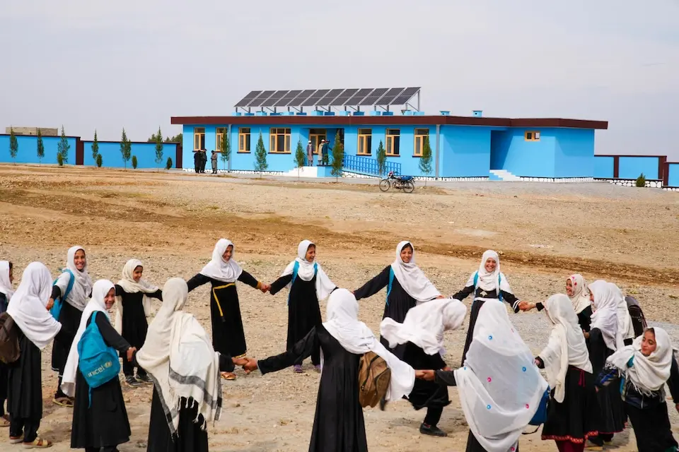 A group of joyful students play a traditional game outside their new UNICEF-built school in Nazyan district, Nangarhar province, Afghanistan.