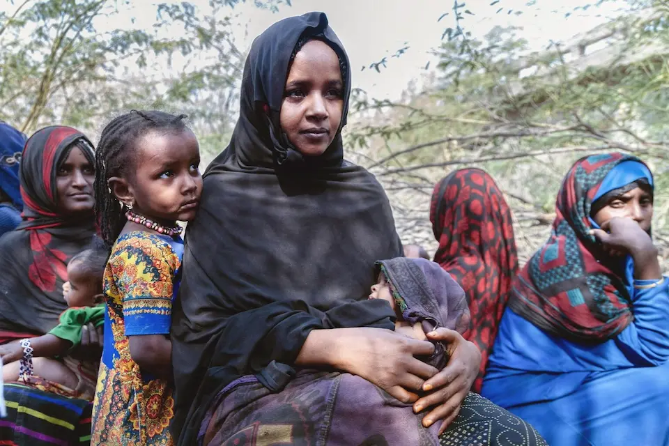 On March 16, 2025 in Ethiopia, a mother holds her baby at a site where children and families have gathered to be seen by a UNICEF-supported mobile health and nutrition team in the Afar region.
