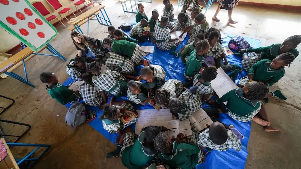 A group of children in Zambia sit together on the floor and work on assignments as part of a catch-up class at Tunduya Elementary School, outside Lusaka, Zambia.