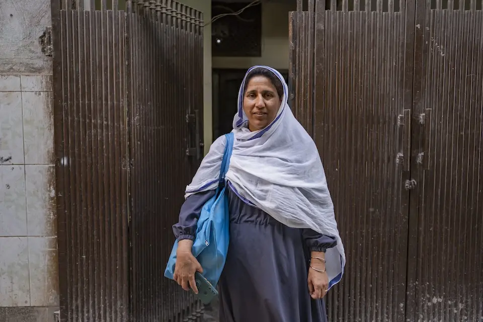 Female village health worker standing in front of house