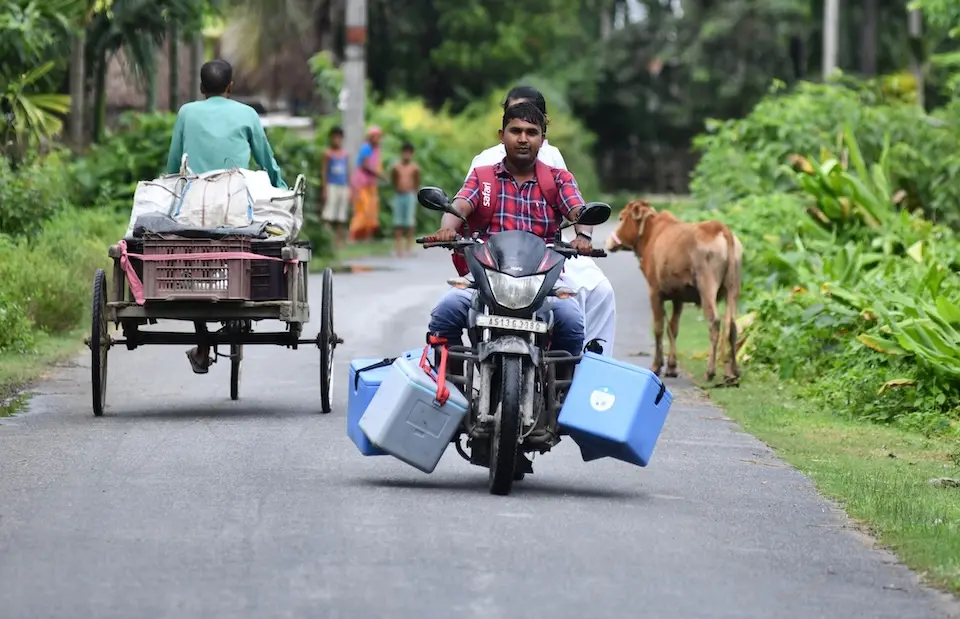 A vaccinator transports cold boxes by motorcycle to reach children in India.