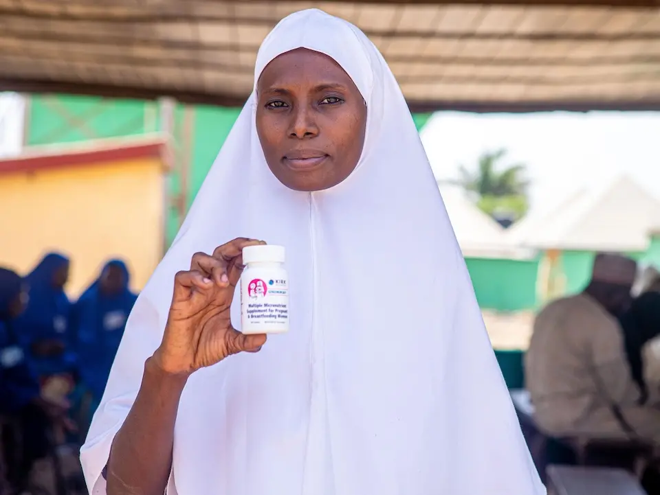 A woman in Nigeria holds a bottle of Multiple Micronutrient Supplements. © UNICEF/UNI761762/Fashina