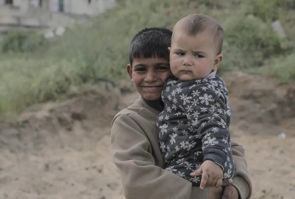 Siraj, 7, holds his little brother in Gaza City on Feb. 20, 2025.