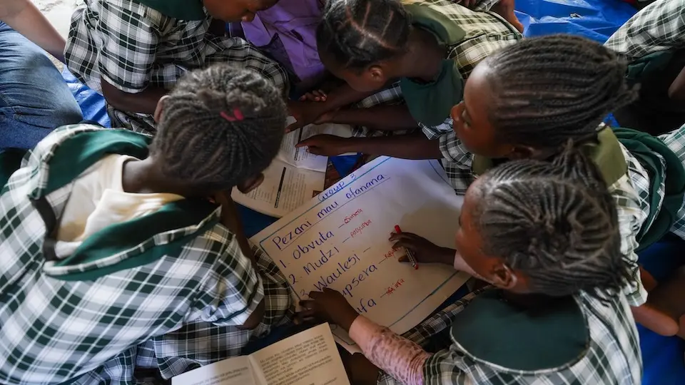 Classmates huddle over a white board at a UNICEF-supported school in Zambia