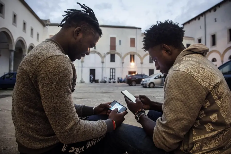 Two young men use their phones in Italy