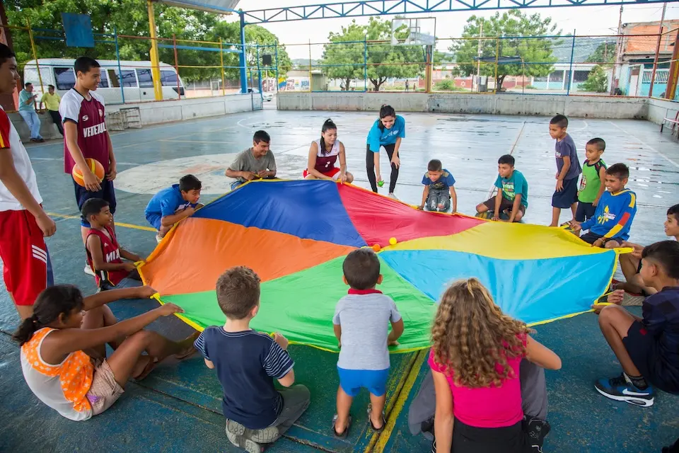 UNICEF Venezuela staff and children play with a parachute at a child-friendly space.