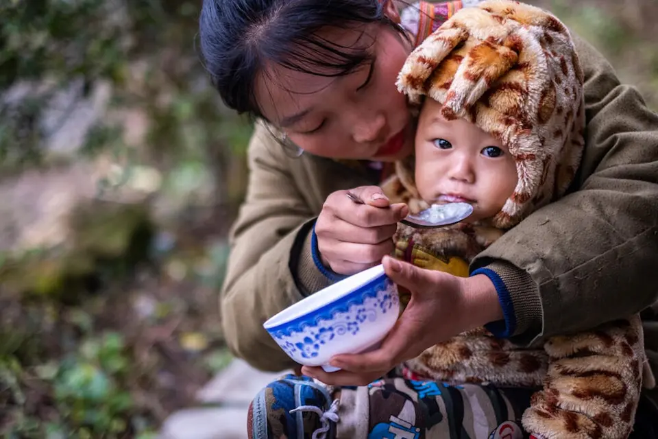 A mother feeds her child in Vietnam through humanitarian aid supported by UNICEF