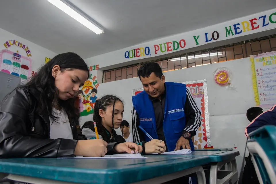 A teacher helps students at their desks in a UNICEF-supported school in Peru. 