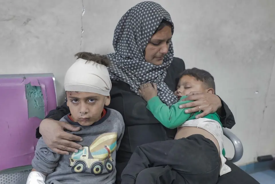 A mother sits with her two young sons, injured during an attack on Dar Al-Arqam School, Gaza City on April 3, 2025, while other family members undergo surgery.